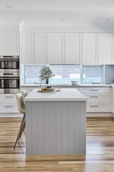 a kitchen with white cabinets and an island in the middle of the room, has a potted plant on top of it