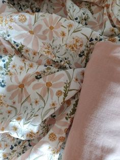 an unmade bed with pink sheets and floral print on the coverlet, next to a pillow