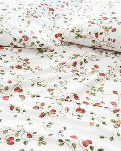 a white bed with red flowers and green leaves on it