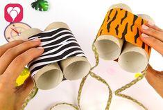 two hands are holding up some toilet paper rolls that look like zebras and tiger stripes