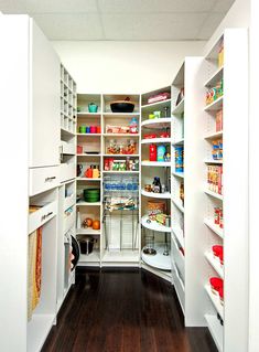 an open pantry filled with lots of food and condiments in white walls, along with wooden flooring