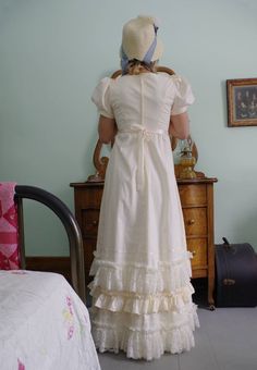 Regency era romantic styled cotton gown with high waist and intricate detail! Ultra-feminine look with short puffed sleeves gathered to cotton bands. The long cotton attached skirt to the fitted bodice has rows of lace, ribbon and cotton ruching at the hem. Skirt is slightly gathered to the fitted bodice. Back zipper closure. Cotton fabric so you can hand wash gently with cold water, lay flat to dry. Designed and made proudly by Recollections in America! Liesa is wearing a petticoat, bonnet,jewe Long Cotton Skirt, Spencer Jacket, Cotton Gowns, Bustle Dress, Burgundy Jacket, Regency Dress, Twill Jacket, Corduroy Dress, Prairie Dress