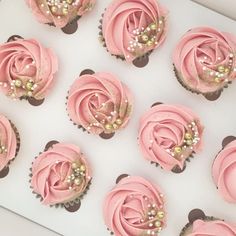 cupcakes with pink frosting and gold sprinkles in a box