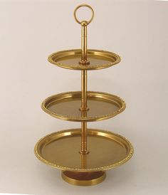 three tiered tray with gold trimmings on each side and a ring at the top