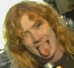 a man with long red hair making a face and sticking his tongue out to the side