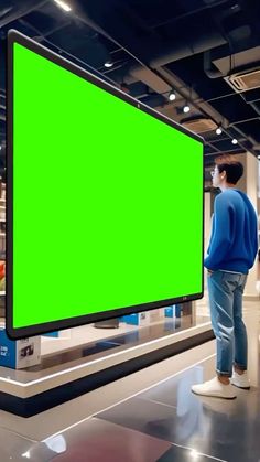 a man is standing in front of a large green screen on the floor at an airport