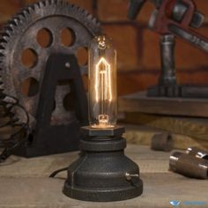 a light bulb sitting on top of a wooden table next to some metal gear and tools