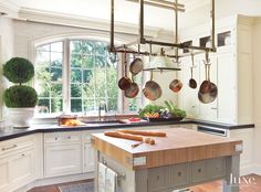 a kitchen with white cabinets and wooden counter tops next to an island in front of a window