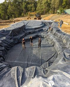 construction workers are working on an outdoor swimming pool that's being built in the middle of a forest