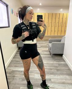 a woman with tattoos taking a selfie in the mirror