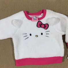 a hello kitty sweater laying on top of a brown couch next to a toothbrush