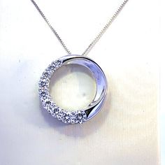 Featuring our stunningly designed 20 inch 14K white gold diamond circle necklace. This modern pendant features 9 - 1.23 carat total weight G/H Si round brilliant cut diamonds situated from the 7 to 11 positions on the circle, giving it a half moon appearance. Pendant measures 20mm in diameter. Pendant has a hidden bail with separation bars so chain can be set in different positions to give the necklace a different look depending on how the chain is attached. Wear day or night for a brilliant statement piece. Diamond Circle Necklace, Diamond Circle Pendant, Circle Pendant Necklace, Circle Diamond, Circle Necklace, Modern Pendant, Circle Pendant, G H, Round Brilliant Cut Diamond