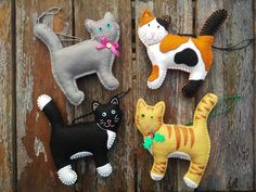 four felt cat ornaments hanging on a wooden fence