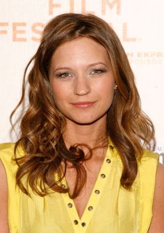 a woman with long brown hair wearing a yellow shirt