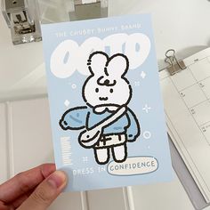 a person holding up a card with an image of a teddy bear on it and the caption reads, the chubby bunny brand dress in confidence