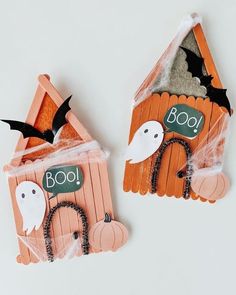 two popsicle houses decorated to look like bats and ghostes with boo written on them