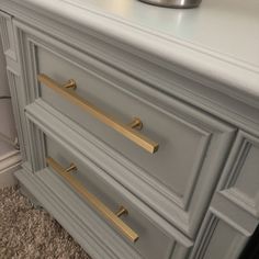 a gray dresser with brass handles and drawers