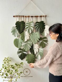 a woman standing in front of a wall hanging plant