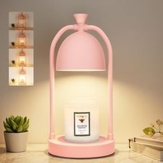 a pink lamp sitting on top of a table next to a potted plant