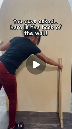 a woman is leaning against a wall with her hand on the back of a skateboard