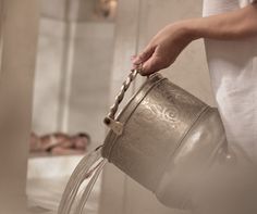 a person holding a metal bucket filled with water