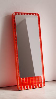 an orange mirror sitting next to a white wall