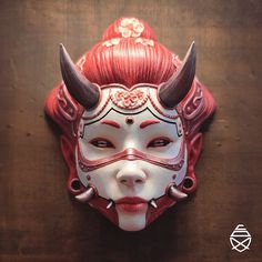 a woman's mask with horns and red hair on a wooden surface in the shape of a demon