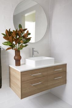 a bathroom with a sink, mirror and vase on the counter top next to it