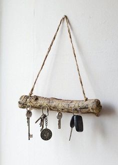 a branch with keys hanging from it is hung on the wall by a rope and some hooks