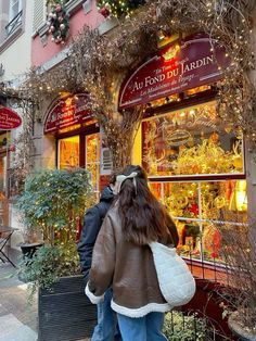 two people are walking in front of a store with christmas decorations on the windows and doors