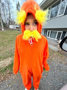 a young child wearing an orange costume with yellow hair and a fake moustache on his face