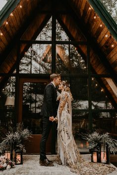 a bride and groom standing in front of a large wooden building with lights on it