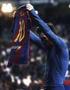 a man holding up a soccer jersey in front of a crowd