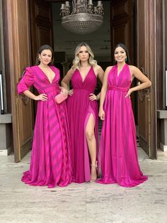 three women in bright pink dresses posing for the camera with their hands on their hips