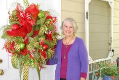 an older woman standing in front of a door with a christmas wreath and decorations on it