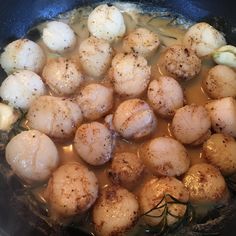 scallops are being cooked in a wok with broth and seasoning