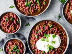 four bowls of chili with sour cream and cilantro garnished with parsley