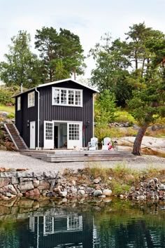 a small black house sitting on top of a lake