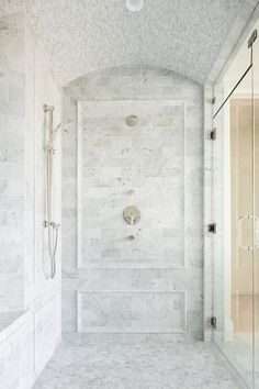 a walk in shower sitting next to a white tiled wall and counter top under a light fixture