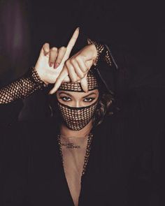 a woman with her hands in the air while wearing a mask and pointing to the side