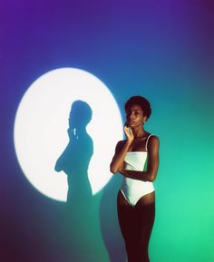 a woman standing in front of a wall with a shadow on it