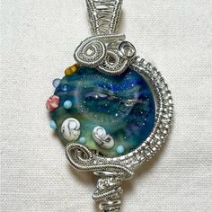 Stunning. Unique Wire Wrapped Ocean Design Pendant In Gorgeous Blue, Indigo, Green Hues. 2 Inches Tall By 1 Inch Wide. Sterling Silver And Resin. Wire Wrapped Jellyfish, Artistic Blue Beaded Necklace, Whimsical Round Blue Jewelry, Whimsical Blue Round Jewelry, Unique Handmade Blue Necklaces, Artistic Blue Beaded Jewelry, Whimsical Blue Pendant Jewelry, Artistic Blue Nickel-free Jewelry, Handmade Blue Glass Necklaces