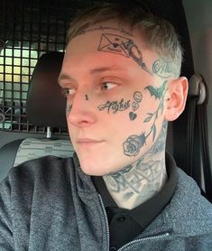 a man with tattoos on his face and neck sitting in the back seat of a car