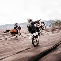 two people are riding motorcycles in the dirt while another person is on horseback behind them