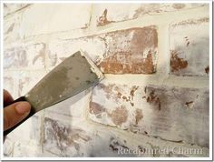 a person holding a knife in front of a brick wall that has been chipped