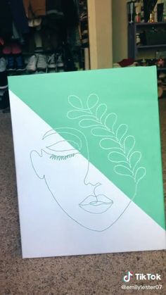 a green and white canvas with a drawing of a woman's face on it