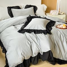 a bed with black ruffled bedspread and pillows