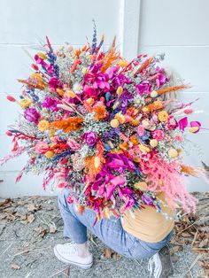 a person kneeling down with a bouquet on their head in front of a white wall