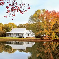 a white house sitting on top of a lake surrounded by trees