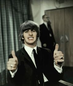 a man in a suit giving the thumbs up